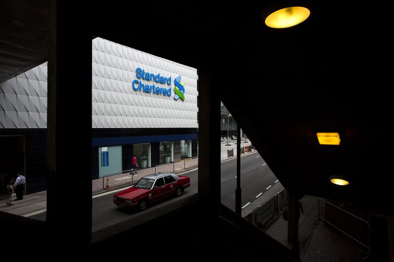 © Reuters. An office worker walks past a Standard Chartered logo outside its head office in Singapore