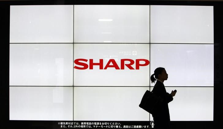 © Reuters. File photo of a pedestrian walking past a logo of Sharp Corp at a train station in Tokyo