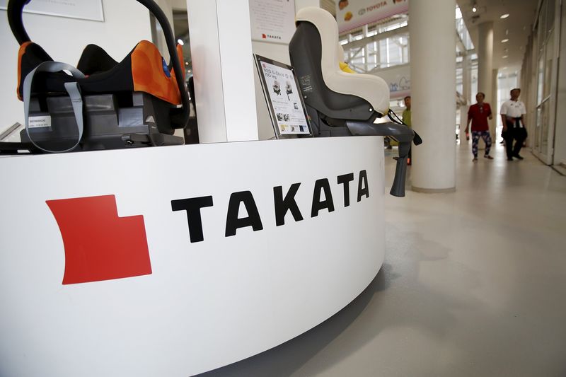 © Reuters. Visitors walk past a logo of Takata Corp on its display at a showroom for vehicles in Tokyo, Japan