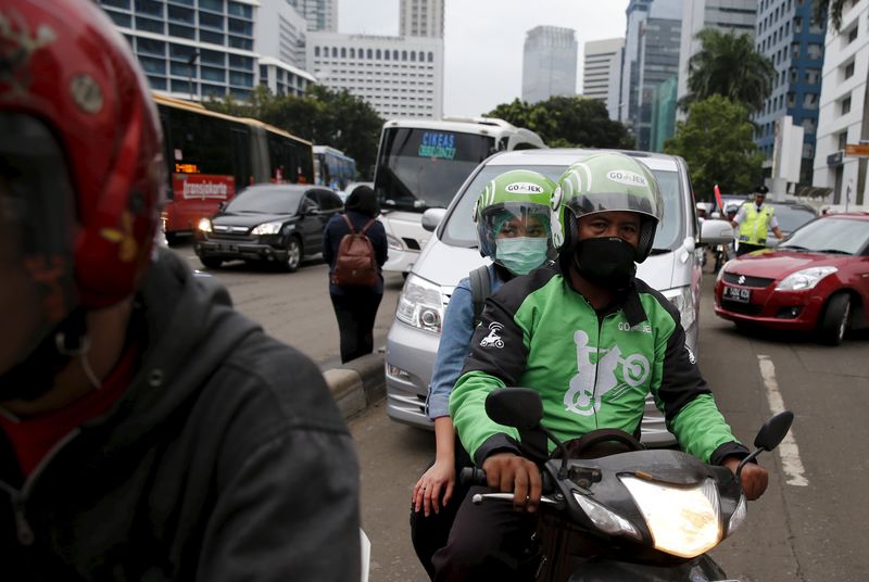 © Reuters. Online motorbike taxi drivers use their smartphones while waiting for customers at a shelter in Jakarta