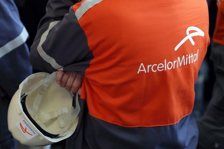© Reuters. Workers stand near the logo of ArcelorMittal at the steel plant in Ghent
