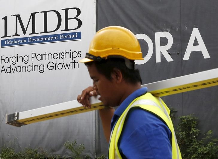 © Reuters. A man walks past a 1 Malaysia Development Berhad (1MDB) billboard at the funds flagship Tun Razak Exchange development in Kuala Lumpur