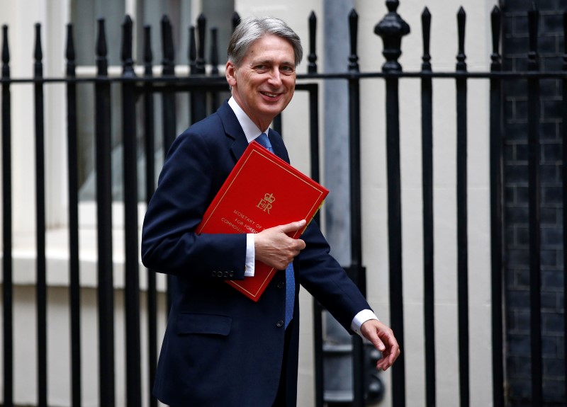 © Reuters. An aide carries Britain's Chancellor of the Exchequer Philip Hammond's ministerial briefcase as she and Hammond leave 11 Downing Street ahead of the Chancellor delivering his Autumn Statement in the House of Commons, in London