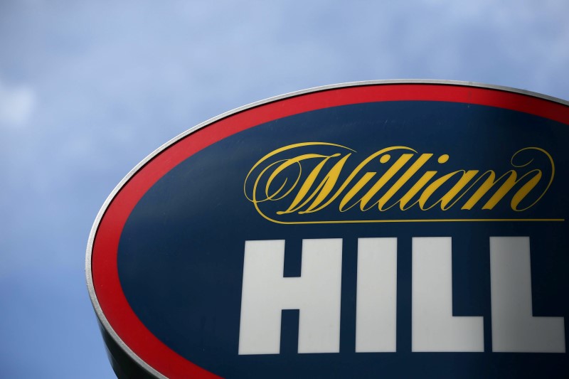 © Reuters. FILE PHOTO: A man walks past a branch of bookmaker William Hill in central London