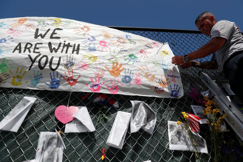 &copy; Reuters. FILE PHOTO: A member of the Miami-Dade Fire Rescue unit places a sign on a makeshift memorial for the victims of the Surfside's Champlain Towers South condominium collapse in Miami, Florida, U.S., July 8, 2021. REUTERS/Shannon Stapleton