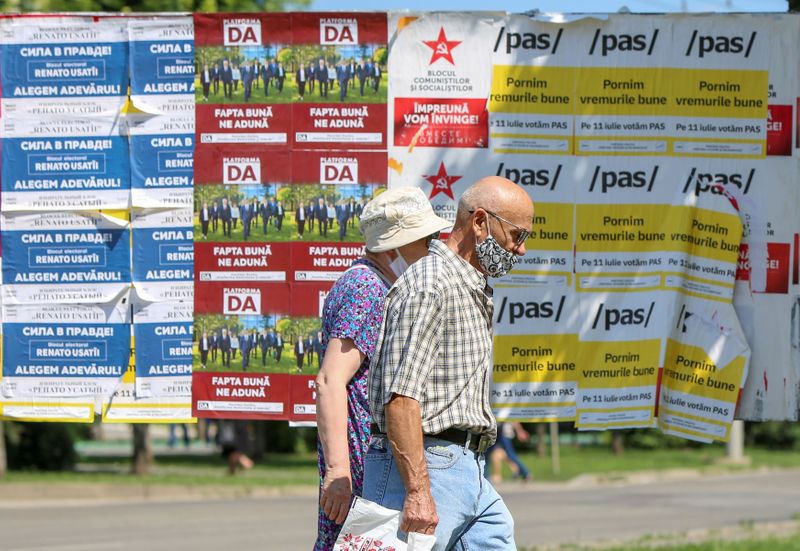 &copy; Reuters. أشخاص يمرون بجوار ملصقات انتخابية قبيل الانتخابات البرلمانية في كيشيناو يوم السابع من يوليو تموز 2021. تصوير: فلاديسلاف كوليومزا - رويترز