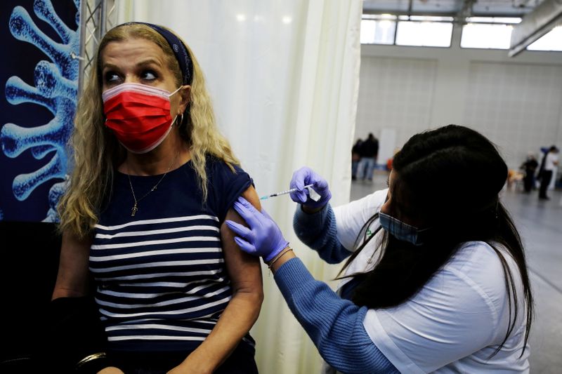 &copy; Reuters. FILE PHOTO: A woman receives a vaccination against the coronavirus disease (COVID-19) at a temporary Clalit healthcare maintenance organisation (HMO) centre, at a basketball court in Petah Tikva, Israel January 28, 2021. REUTERS/Ammar Awad 
