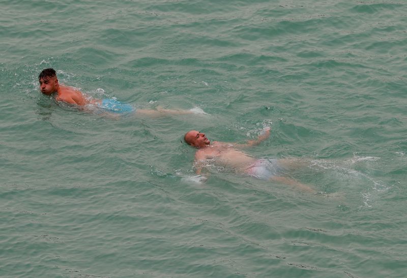 &copy; Reuters. رجلان يستمتعان بالسباحة في إل تشورو بإسبانيا يوم الاحد. تصوير: جون نازكا - رويترز. 