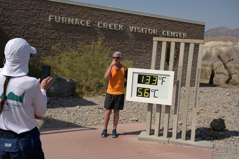 © Reuters. A person poses for a photo next to a thermometer in Death Valley, California, U.S., July 11, 2021. REUTERS/Bridget Bennett  REFILE - CORRECTING CAPTION