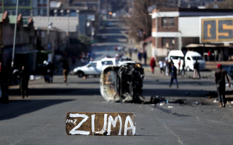 &copy; Reuters. The remains of a burnt car and a sign block the road after stick-wielding protesters marched through the streets, as violence following the jailing of former South African President Jacob Zuma spread to the country's main economic hub in Johannesburg, Sou