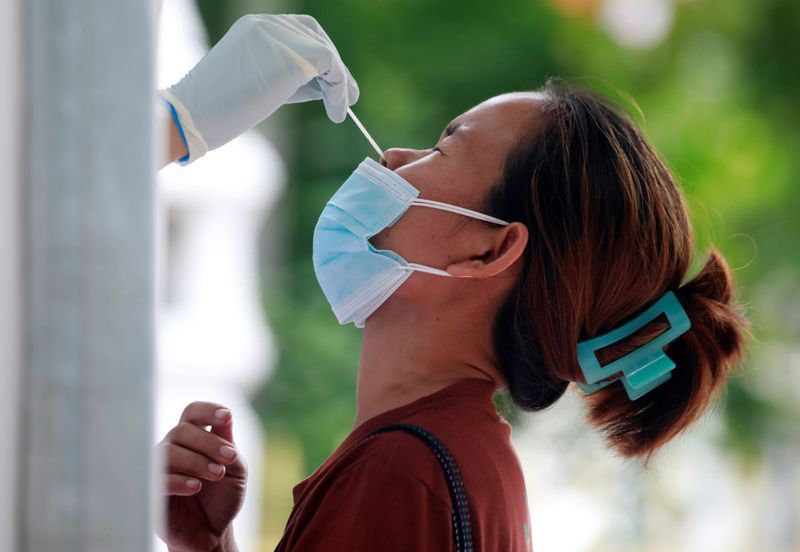 © Reuters. A woman gets a free coronavirus disease (COVID-19) test after queueing overnight at a temple in Bangkok, Thailand, July 10, 2021. REUTERS/Soe Zeya Tun