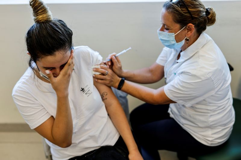 © Reuters. FILE PHOTO: A teenager receives a dose of a vaccine against the coronavirus disease (COVID-19) after Israel approved the usage of the vaccine for youngsters aged 12-15, at a Clalit healthcare maintenance organisation in Ashkelon, Israel June 6, 2021. REUTERS/Amir Cohen/File Photo