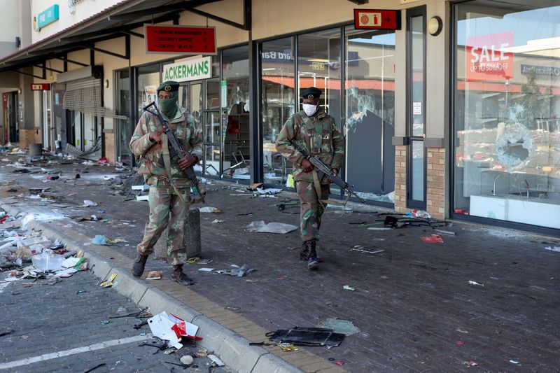 &copy; Reuters. أفراد من الجيش في دورية يمرون بمتاجر تعرضت لأعمال نهب في سويتو بجنوب أفريقيا يوم الثلاثاء. تصوير: سيفوي سيبكو - رويترز.