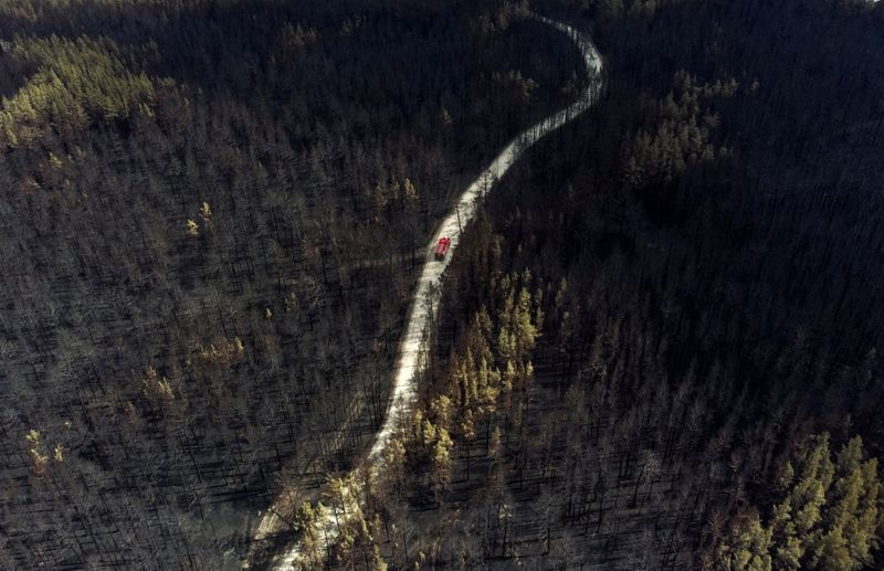 &copy; Reuters. A fire truck drives across a forest burnt by wildfire towards to the sattelment of Zapasnoye in Chelyabinsk Region, Russia July 12, 2021. Picture taken with a drone.  REUTERS/Alexey Malgavko     