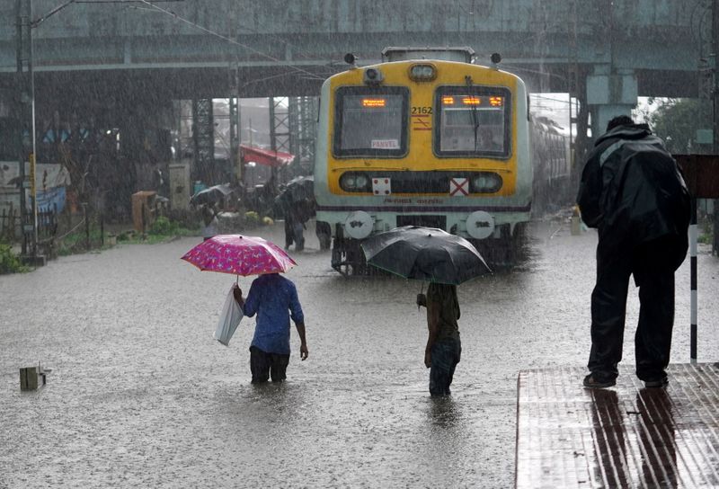 &copy; Reuters. Pessoas cruzam trilhos de trem inundados ao lado de um trem de passageiros estacionado durante fortes chuvas de monções em Mumbai, Índia
09/07/2021
REUTERS/Hemanshi Kamani