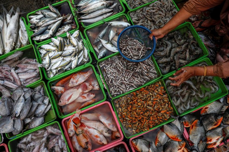 &copy; Reuters. FILE PHOTO: A vendor selling seafood prepares fish as she serves her customers, at a traditional market in Jakarta, Indonesia, March 1, 2021. REUTERS/Willy Kurniawan/File Photo