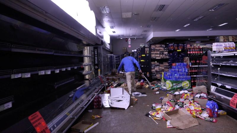 &copy; Reuters. FILE PHOTO: A self-armed local looks for looters inside a supermarket following protests that have widened into looting, in Durban, South Africa July 13, 2021, in this screen grab taken from a video. Courtesy Kierran Allen/via REUTERS