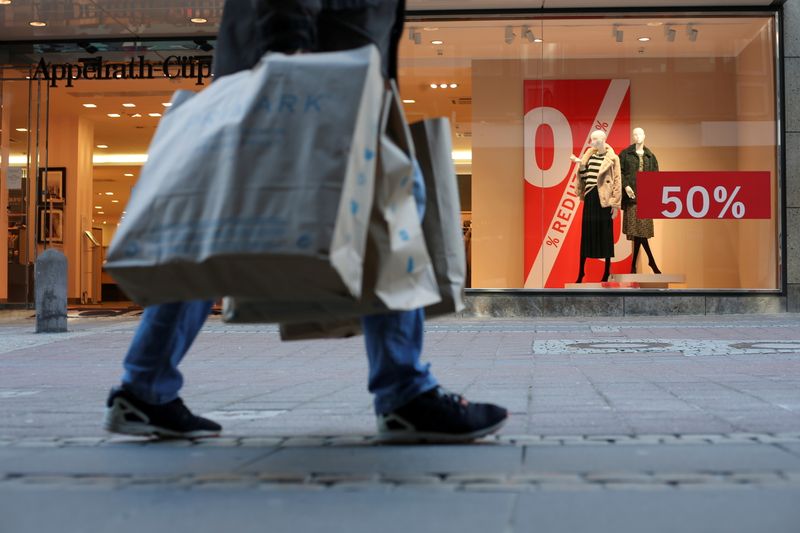 &copy; Reuters. A person holding shopping bags walks past a store as the coronavirus disease (COVID-19) lockdown measures are eased in Kiel, Germany, March 9, 2021. REUTERS/Cathrin Mueller/File Photo 