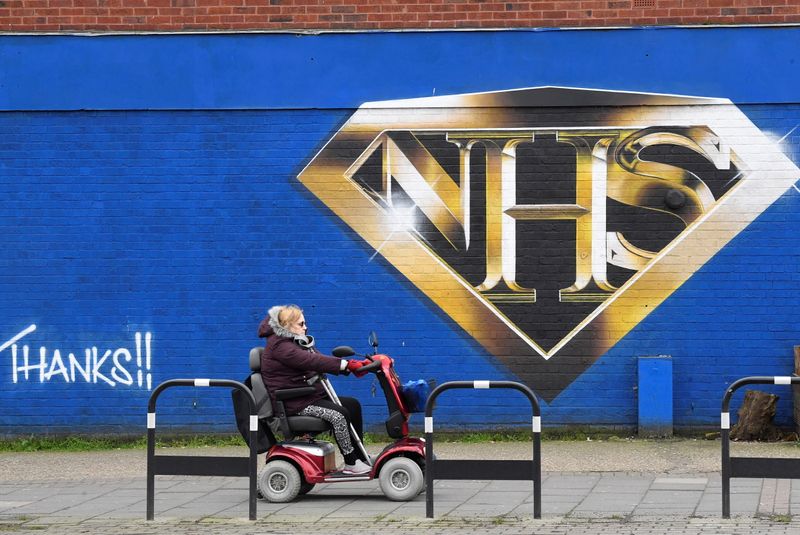 &copy; Reuters. FILE PHOTO:  A woman on a mobility scooter drives past a mural praising the NHS (National Health Service) amidst the continuation of the coronavirus disease (COVID-19) pandemic, London, Britain, March 5, 2021. REUTERS/Toby Melville/File photo
