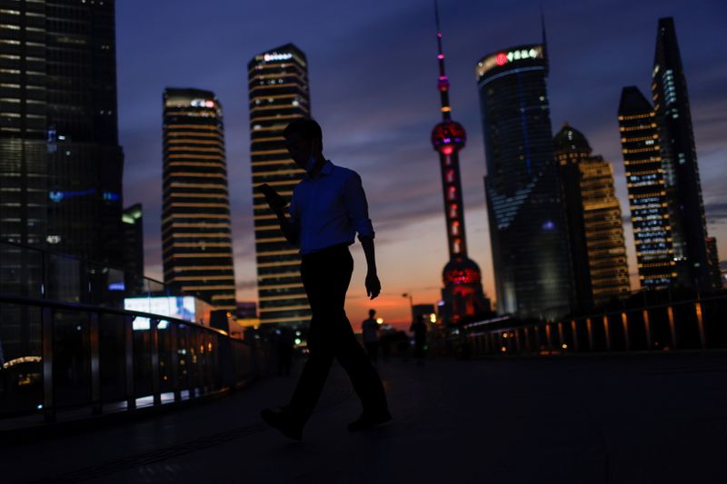 &copy; Reuters. A man checks his phone while walking in Lujiazui financial district during sunset in Pudong, Shanghai, China July 13, 2021. REUTERS/Aly Song
