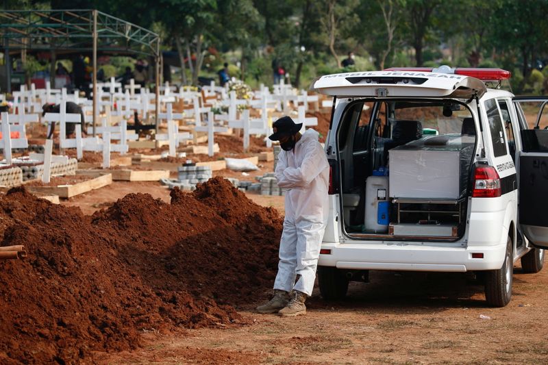 © Reuters. Ujang Sihab, 46, a Local Disaster Management Agency (BPBD) officer who is assigned to be ambulance driver, leans on an ambulance as he delivers the coffin of 72-year-old man who passed away due to coronavirus disease (COVID-19) at a burial area provided by the government COVID-19 victims as the case surges, in Bekasi, on the outskirts of Jakarta, Indonesia, July 15, 2021. REUTERS/Willy Kurniawan