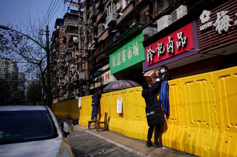 &copy; Reuters. FILE PHOTO: Residents pay for groceries over barriers set up to ring fence a wet market on a street in Wuhan, Hubei province, the epicentre of China's coronavirus disease (COVID-19) outbreak, April 1, 2020. REUTERS/Aly Song