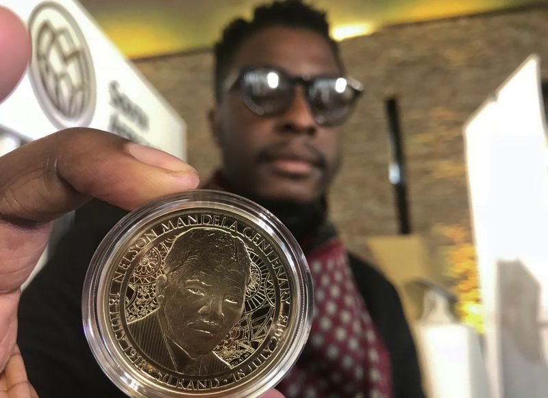 &copy; Reuters. Zimbabwe-born Sindiso Nyoni holds a 1-ounce pure gold 5 rand coin that he designed, as the South African Reserve Bank (SARB) launched a set of limited edition bank notes and gold coins to mark the 100th anniversary of the birth of Nelson Mandela, in Preto