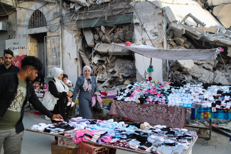 &copy; Reuters. A Palestinian sells socks on a stall near the rubble of his old store that has been destroyed in an Israeli air strike, ahead of Eid Al-Adha Muslim holiday, in Gaza City, July 14, 2021. Picture taken July 14, 2021. REUTERS/Mohammed Salem