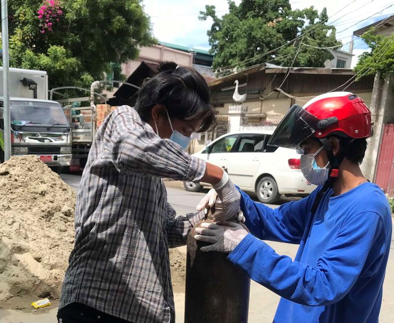 &copy; Reuters. A volunteer fills an oxygen tank as coronavirus disease (COVID-19) cases surge in Mandalay, Myanmar July 13, 2021. Picture taken July 13, 2021. Phoe Thar via REUTERS 