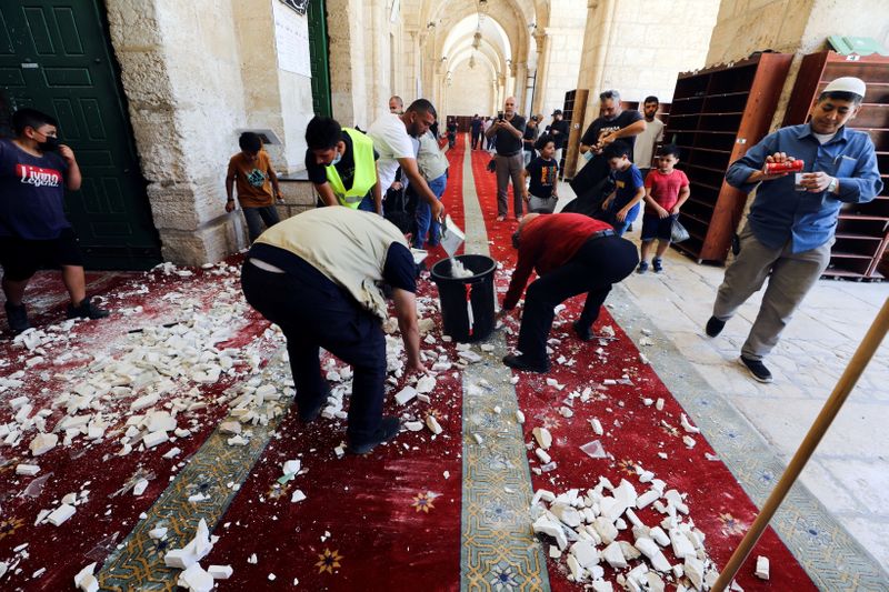 © Reuters. أشخاص يقومون بتنظيف المسجد الأقصى بعد اشتباكات بين مصلين والشرطة الإسرائيلية يوم الاحد. تصوير: عمار عوض - رويترز. 