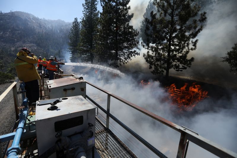 &copy; Reuters. Firefighters assigned to the Union Pacific Fire Train protect the tracks and hinder the Dixie Fire from crossing the North Fork of the Feather River in Plumas National Forest, California, U.S., July 17, 2021.  REUTERS/David Swanson