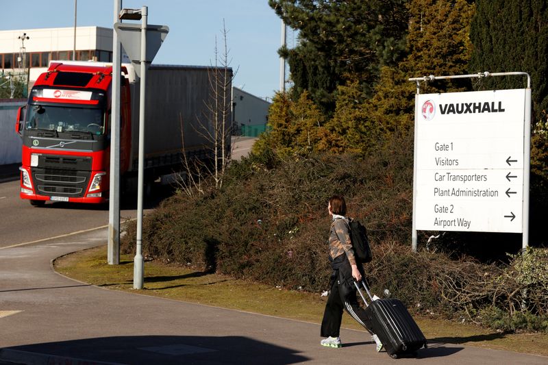 © Reuters. A woman with a luggage passes by a sign of The Vauxhall plant closed as the outbreak of the coronavirus disease (COVID-19) continues, in Luton, Britain March 16, 2020. REUTERS/John Sibley/Files