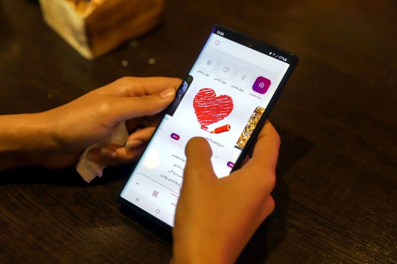 &copy; Reuters. امرأة إيرانية تراجع تطبيق "همدم" للمواعدة على هاتفها المحمول في مقهى في العاصمة طهران يوم 17 يوليو تموز 2021. 
(صورة لرويترز من وكالة غرب آسيا لل