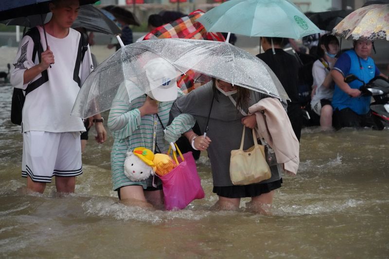 &copy; Reuters. Residentes caminan a través de las aguas de la inundación en una carretera en Zhengzhou, provincia de Henan, China 20 de julio de 2021. cnsphoto via REUTERS 