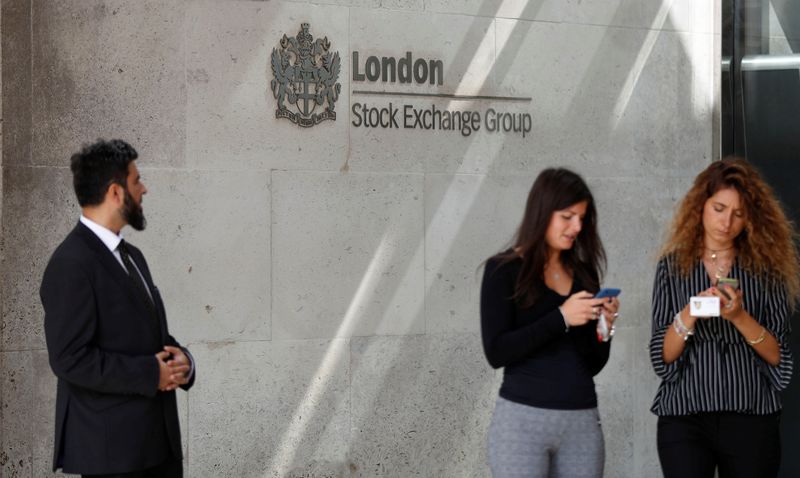 &copy; Reuters. FILE PHOTO:  People check their mobile phones as they stand outside the entrance of the London Stock Exchange in London, Britain. Aug 23, 2018. REUTERS/Peter Nicholls/File photo