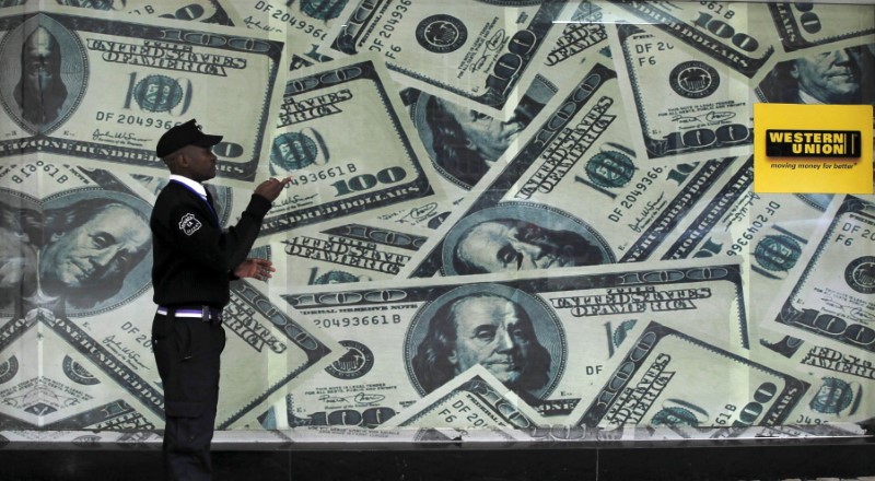&copy; Reuters. FILE PHOTO: A security guard walks past a montage of old U.S. dollar bills outside a currency exchange in Kenya's capital Nairobi July 23, 2015. REUTERS/Thomas Mukoya/File Photo