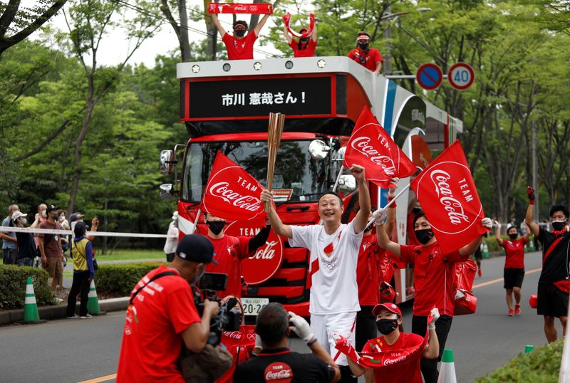 &copy; Reuters. A torchbearer celebrates with Coca Cola sponsor stuff as he waits for his turn to run during the Tokyo 2020 Olympic torch relay on the first day of the relay, amid the coronavirus disease (COVID-19) outbreak, in Asaka, Saitama prefecture, Japan July 6, 20