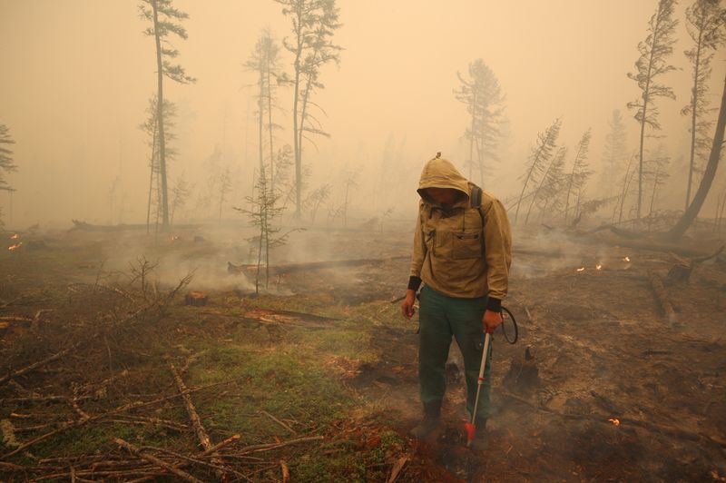 © Reuters. FILE PHOTO: A specialist of the local forest protection service works to extinguish a forest fire near the village of Magaras in the region of Yakutia, Russia July 17, 2021. Picture taken July 17, 2021. REUTERS/Roman Kutukov/File Photo