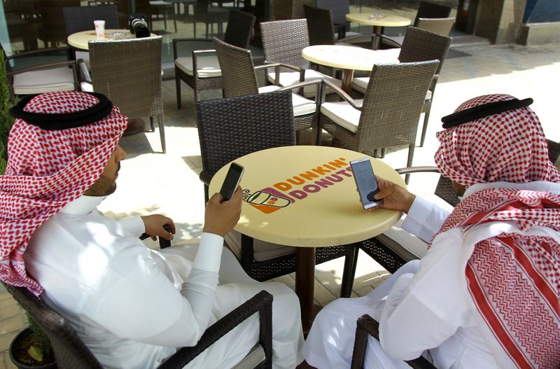 &copy; Reuters. سعوديان يطالعان هاتفيهما في مقهى بالرياض. صورة من أرشيف رويترز
