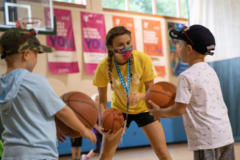 © Reuters. FILE PHOTO: A counselor wearing a protective face mask plays with children as summer camps reopen amid the spread of coronavirus disease (COVID-19) at Carls Family YMCA summer camp in Milford, Michigan, U.S., June 23, 2020.  REUTERS/Emily Elconin