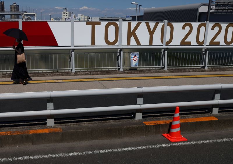 &copy; Reuters. A person walks past an Olympics advertisement, as seen from a special bus that transports journalists to and from the facilities and media center ahead of the Tokyo 2020 Olympic Games in Tokyo, Japan, July 21, 2021. REUTERS/Leah Millis   REFILE - CORRECTI