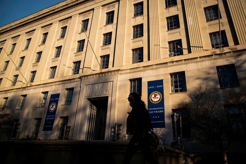 &copy; Reuters. FILE PHOTO: A woman walks past the U.S. Department of Justice Building, in Washington, U.S., December 15, 2020. REUTERS/Al Drago