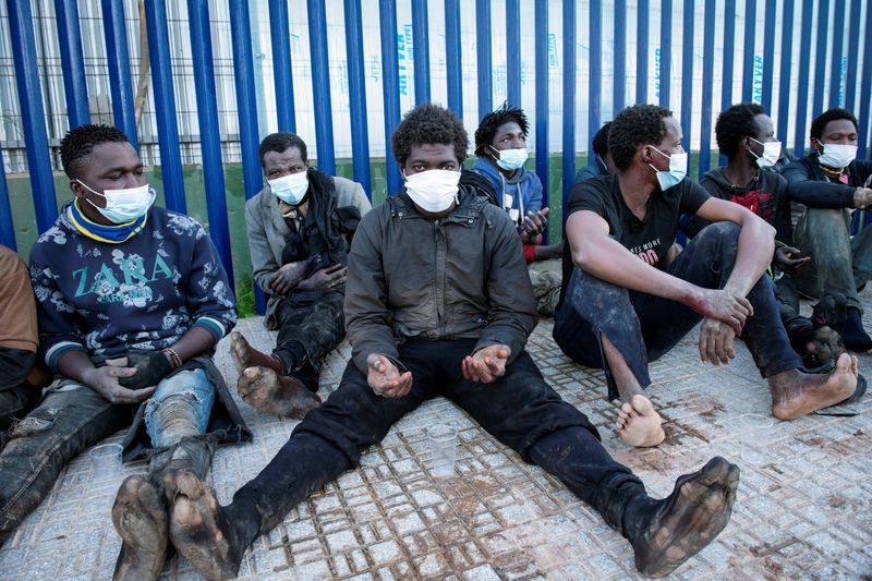 &copy; Reuters. FOTO DE ARCHIVO: Migrantes sentados fuera del centro temporal de migrantes tras cruzar la valla fronteriza en el enclave norteafricano de Melilla, España, 19 de enero de 2021. REUTERS/Jesús Blasco de Avellaneda