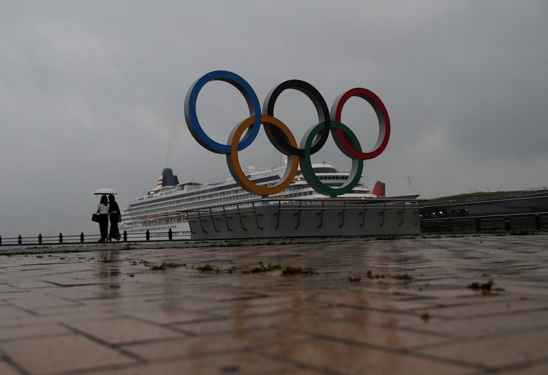 &copy; Reuters. Una mujer con un paraguas pasa por delante de los anillos olímpicos recién instalados para celebrar los Juegos Olímpicos de Tokio 2020 en Yokohama, Japón, 30 de junio de 2021. REUTERS/Kim Kyung-Hoon