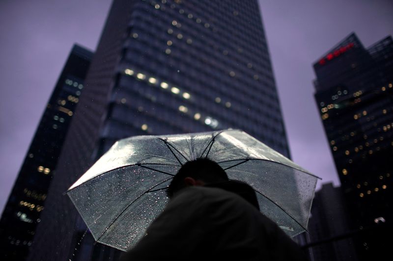 &copy; Reuters. FILE PHOTO: A man walks with an umbrella in Lujiazui financial district in Pudong, following the coronavirus disease (COVID-19) outbreak in Shanghai,  China September 17, 2020. REUTERS/Aly Song