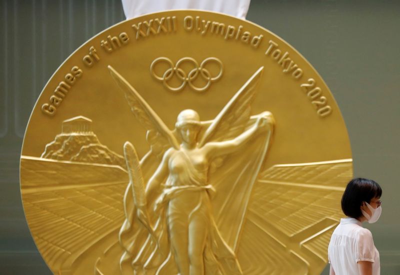 &copy; Reuters. Mulher usando máscara passa em frente à reprodução em larga escla de medalha de ouro da Olimpíada Tóquio 2020 na Torre Nihonbashi Mitsui, em Tóquio
14/07/2021 REUTERS/Kim Kyung-Hoon