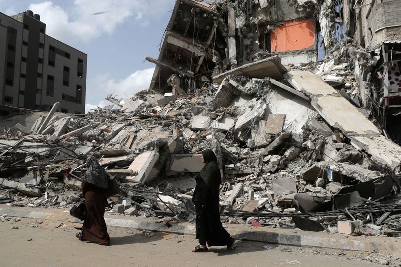 &copy; Reuters. FILE PHOTO: Palestinians walk past the ruins of a building destroyed in an Israeli air strike in the recent cross-border violence between Palestinian militants and Israel, in Gaza May 21, 2021. REUTERS/Suhaib Salem