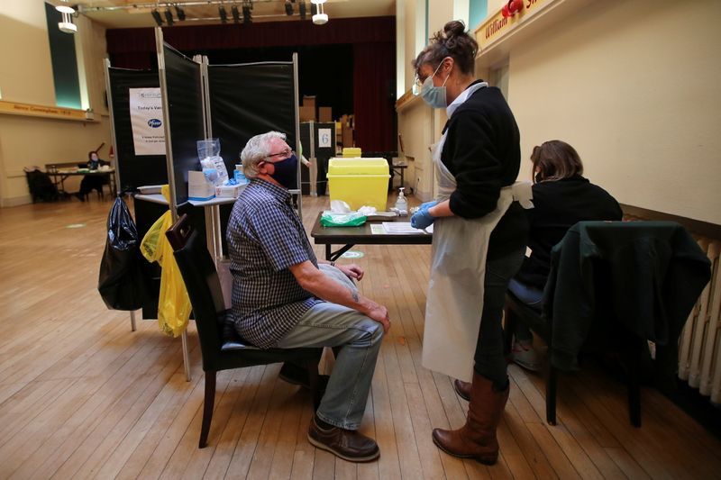 &copy; Reuters. FILE PHOTO: A healthcare worker speaks with an elderly person before administering a dose of the Pfizer-BioNTech coronavirus disease (COVID-19) vaccine at Thornton Little Theatre managed by Wyre Council in Lancashire, Britain January 29, 2021. REUTERS/Mol