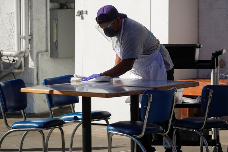 © Reuters. FILE PHOTO: A worker clears and cleans a table along the sidewalk outside 