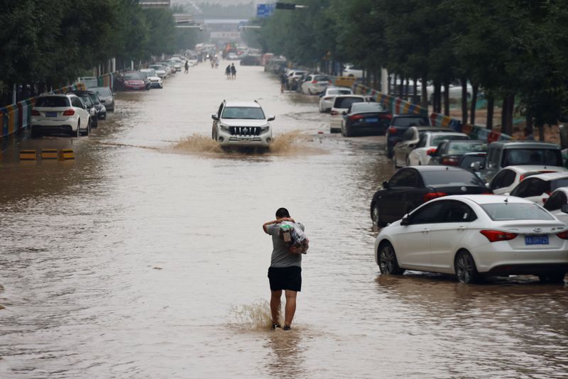 &copy; Reuters. A man wades through a flooded road following heavy rainfall in Zhengzhou, Henan province, China July 23, 2021. REUTERS/Aly Song